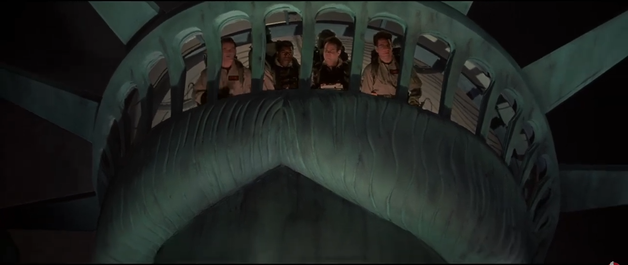 The Ghostbusters are piloting the Statue of Liberty, looking out through her crown.